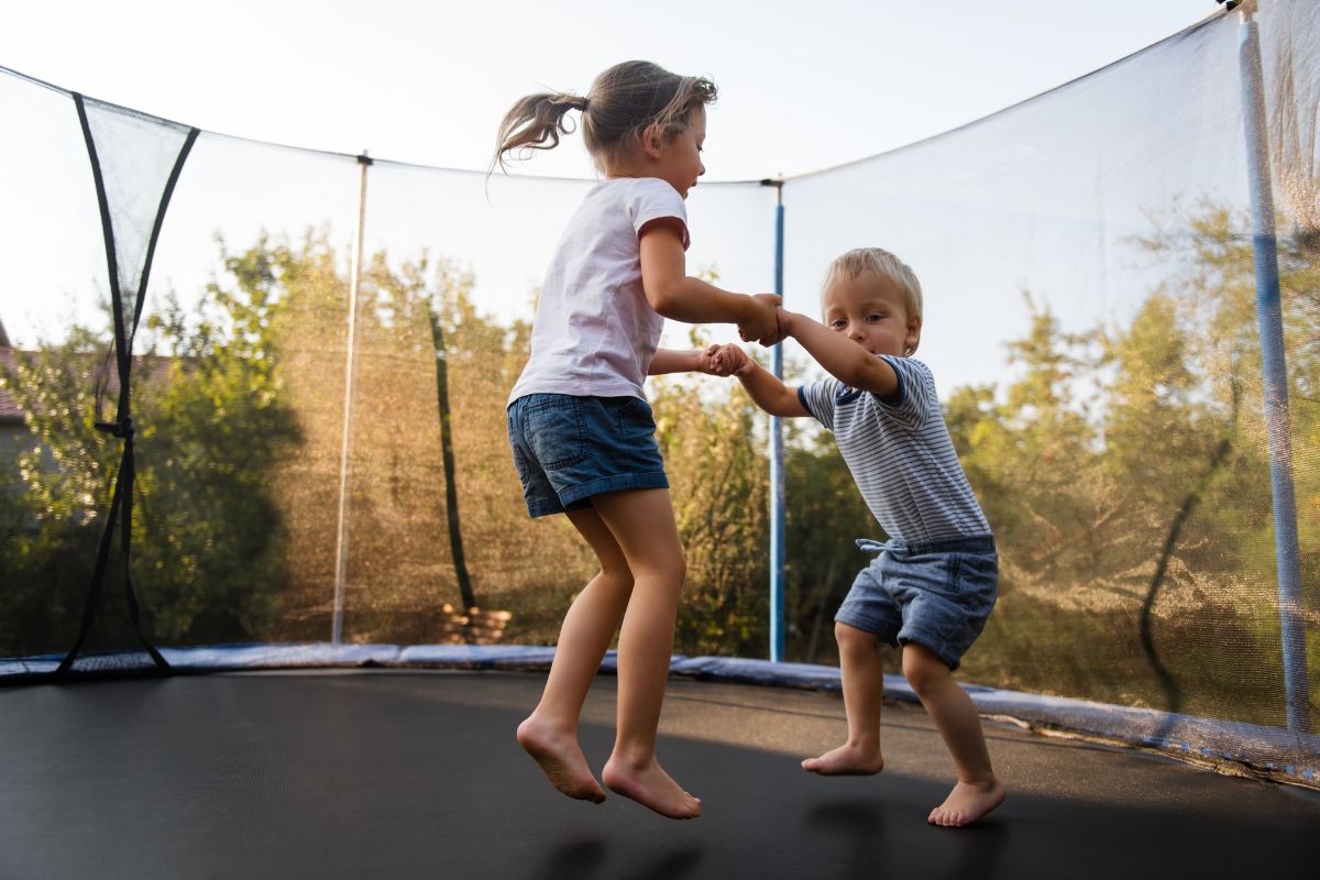 Children bouncing happily on a backyard trampoline